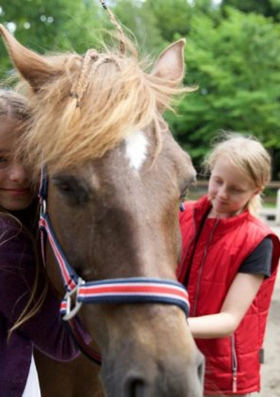 2 piger står ved en hest